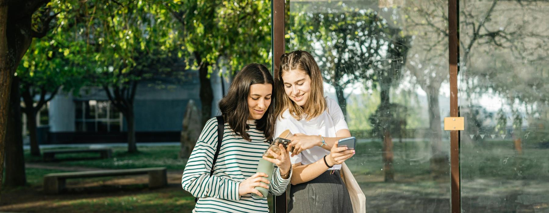 a couple of women standing next to a bus stop