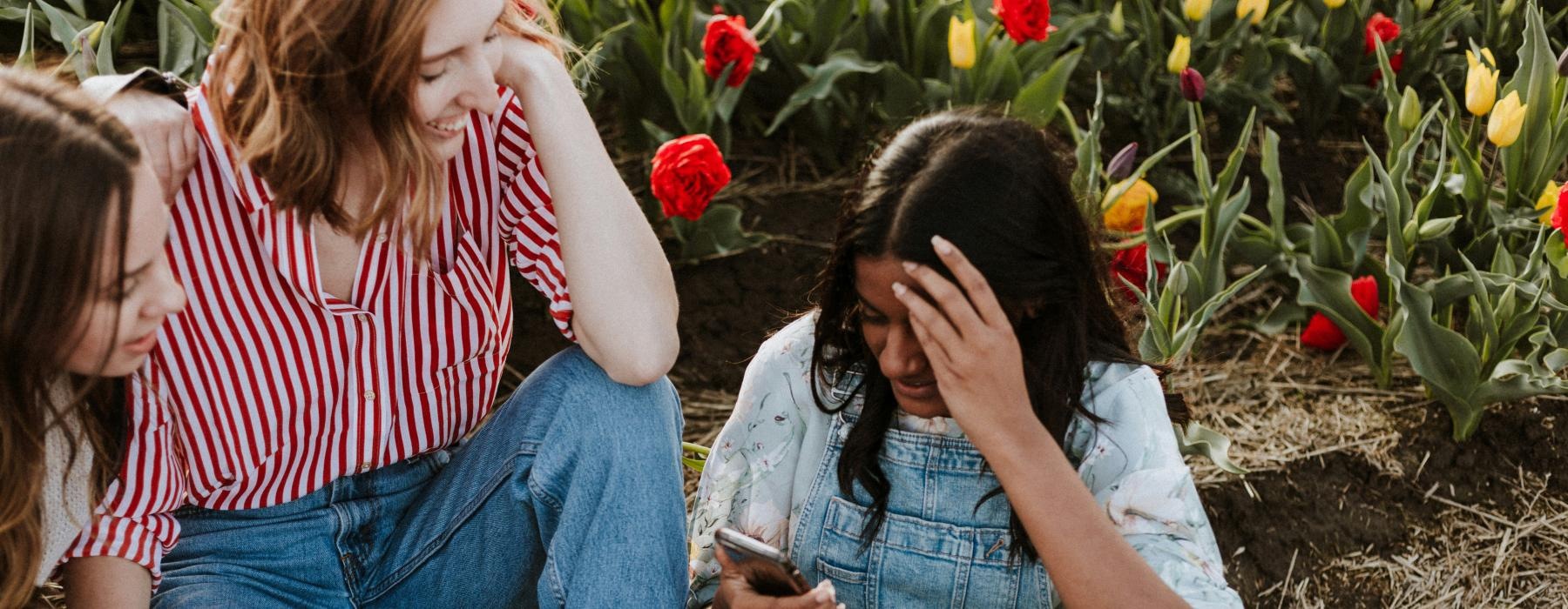 a group of women sitting on the ground looking at their phones