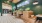 Contemporary lounge area featuring wooden booth seating with brown leather cushions, green accent walls, hanging pendant lights, and built-in planters, creating a warm and inviting atmosphere.